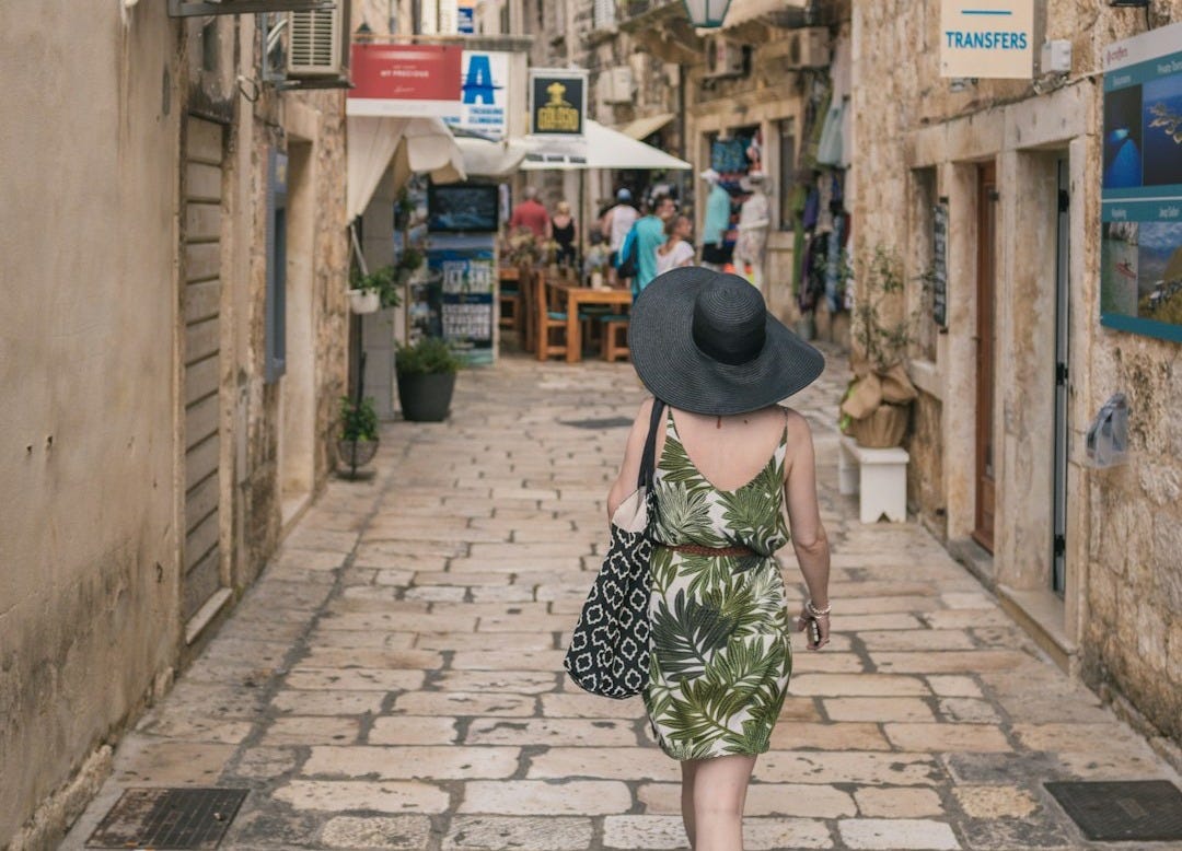 woman walking between brown concrete buildings during daytime
