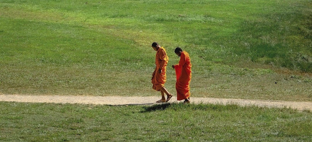 Two monks walking in front of a large building Two monks walking in front of a large building
