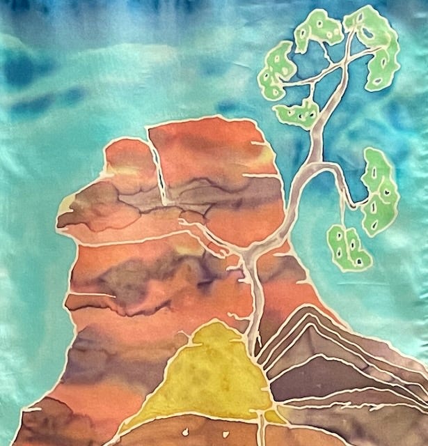 A fig tree clings to a rocky surface in this detail of a hand-painted silk banner. Created by Gwendolyn Hustvedt, “Heart Root” visualizes the tree’s descent toward an unseen underground river, symbolizing resilience in late summer. 