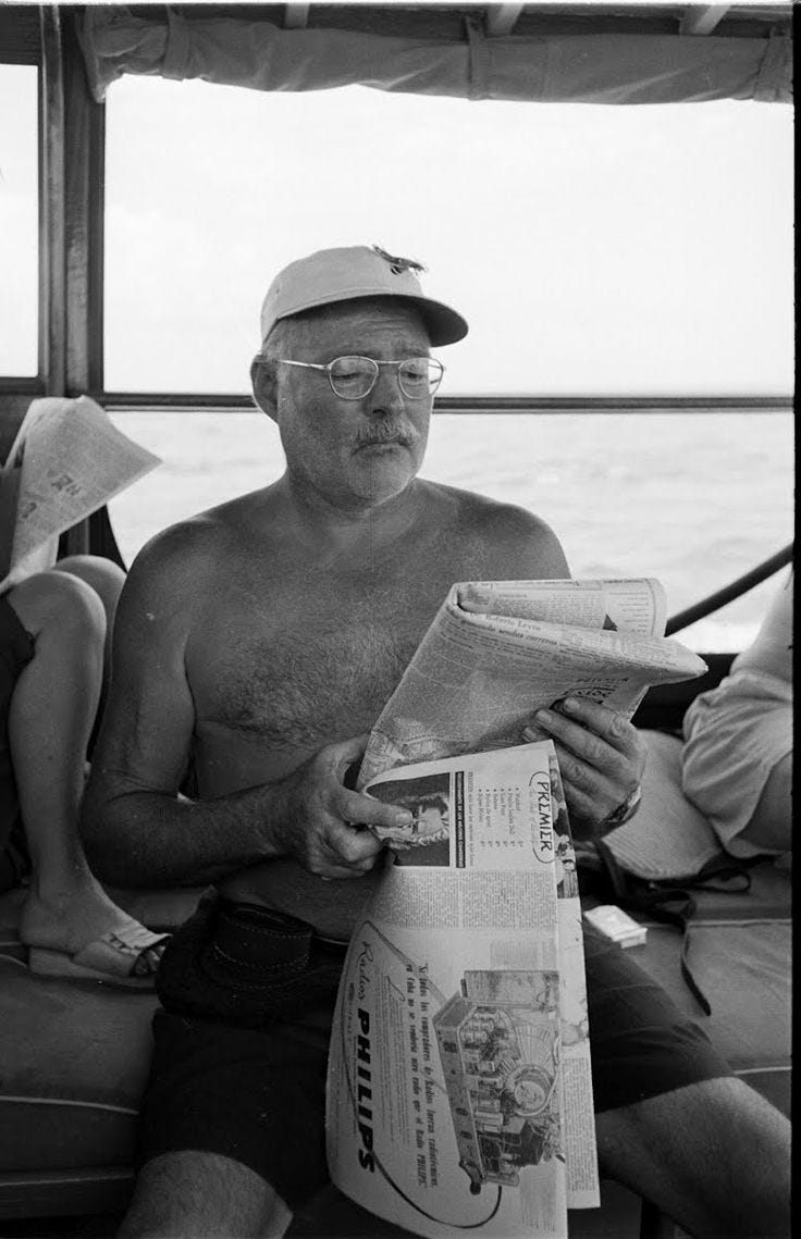 This may contain: a man reading a newspaper while sitting on a boat