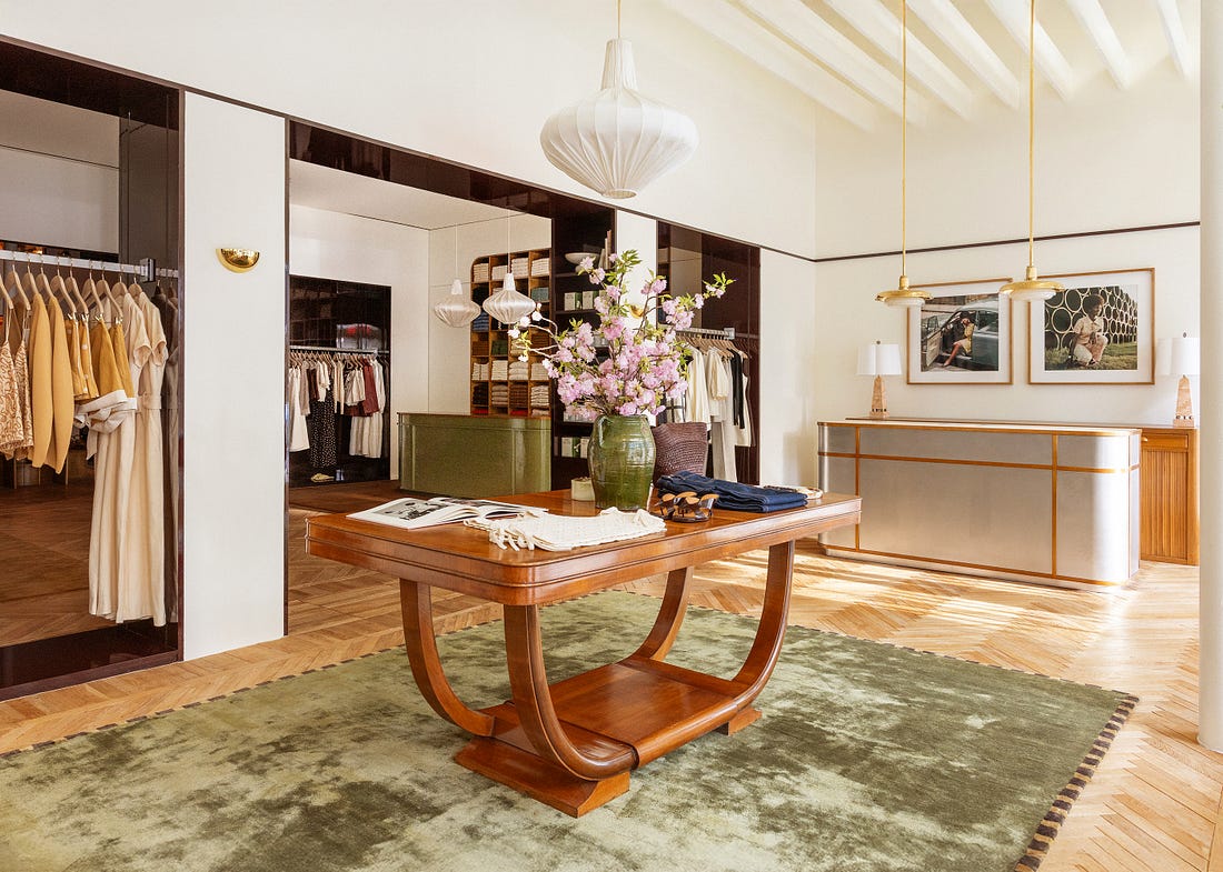 The store interior, with hardwood floors, a velvety green rug, and racks of clothing