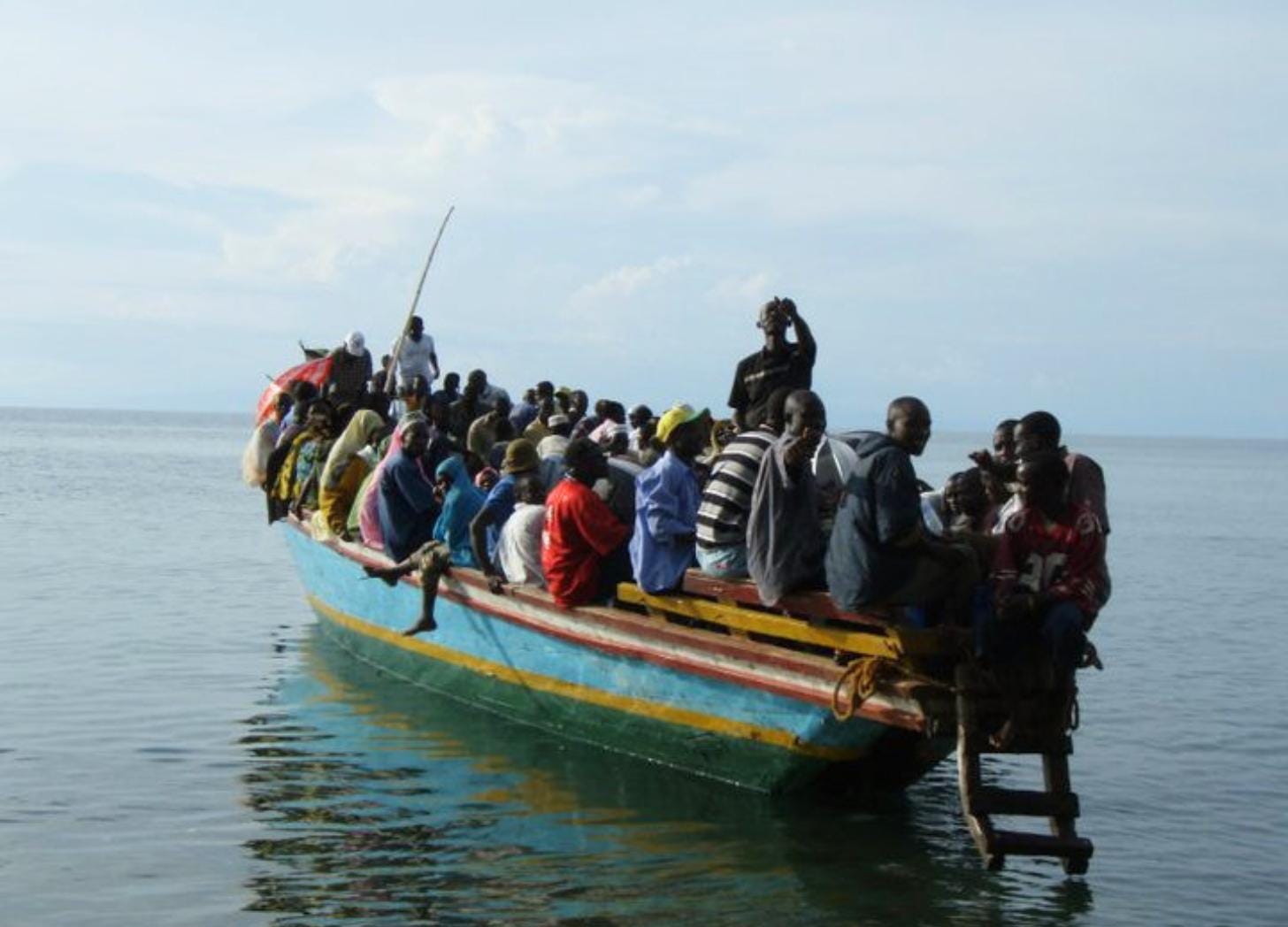 Wooden passenger boat heavily loaded with people crossing Lake Tanganyika under a hazy sky. Wooden passenger boat heavily loaded with people crossing Lake Tanganyika under a hazy sky.
