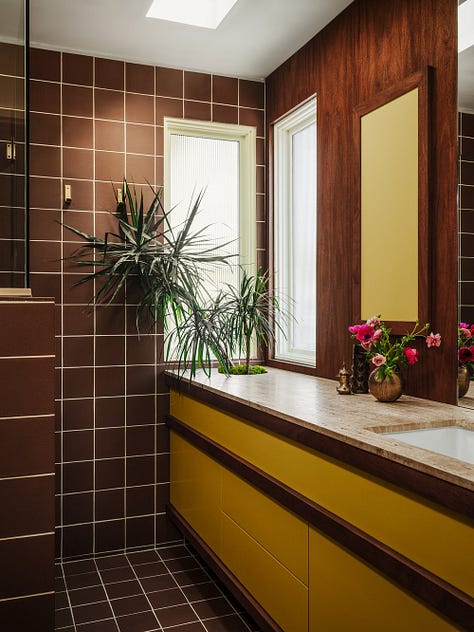 A bathroom with brown tile and yellow details. A green, blue, and purple living room, a primary colored dining room.