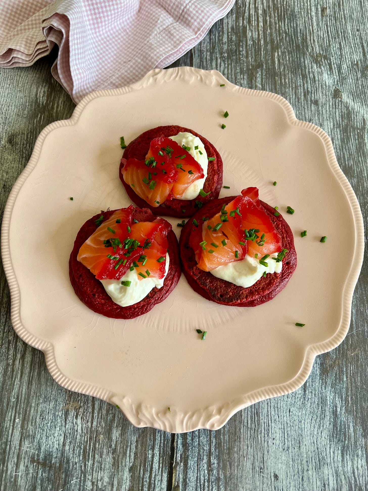 pink beetroot pancakes topped with thin slices of beetroot cured salmon and creme fraiche