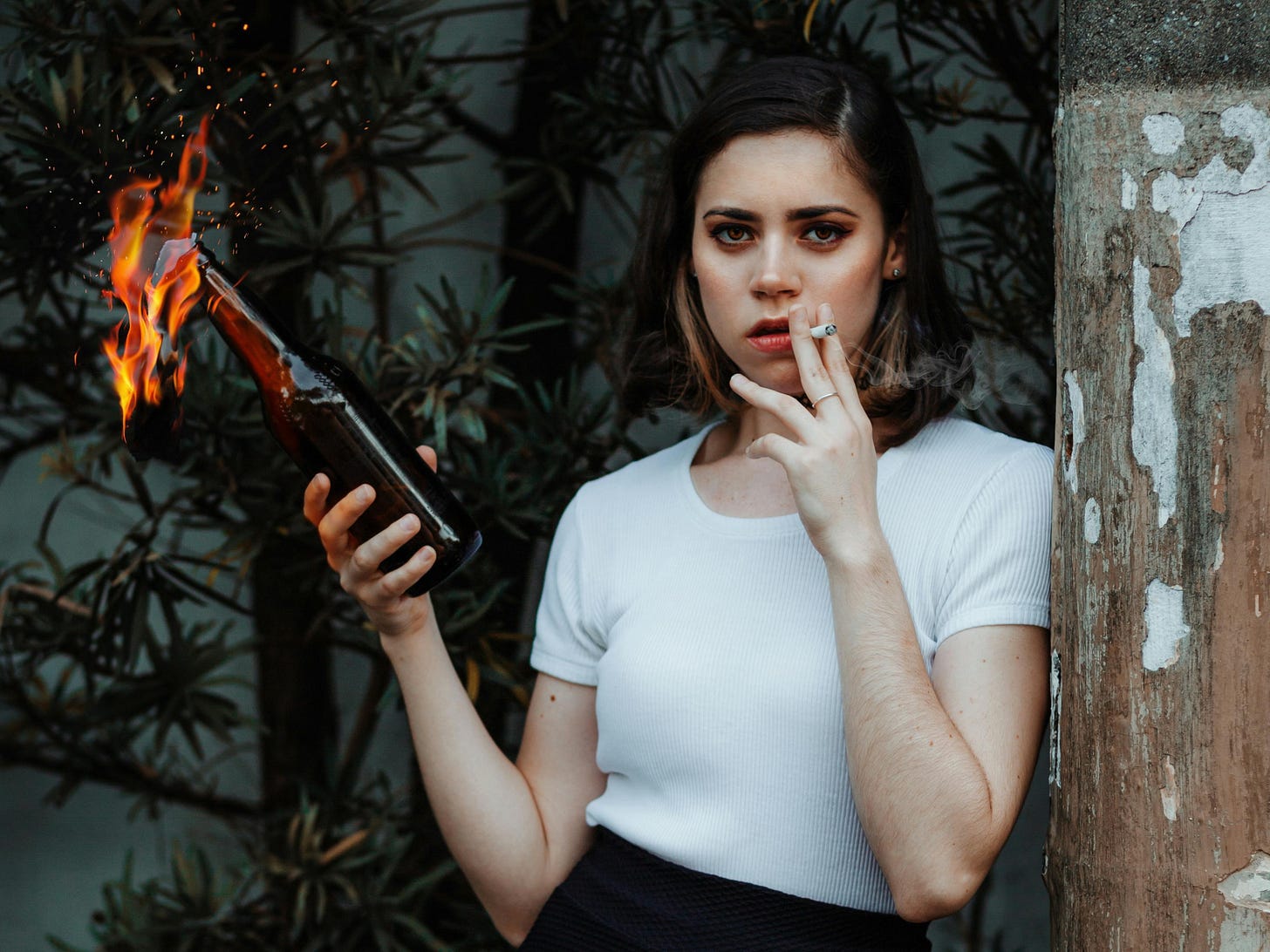 Free Young woman with a molotov cocktail, exuding a rebellious attitude against urban backdrop. Stock Photo Free Young woman with a molotov cocktail, exuding a rebellious attitude against urban backdrop. Stock Photo