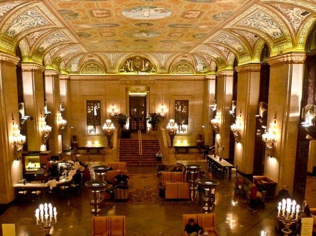 A grand hotel lobby with friezes, arches, sculpture, and elaborate ceiling.