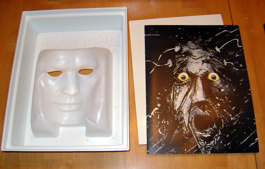 Inside of the original Suspended mask box, showing the plastic mask and the sketch of a screaming man inside.