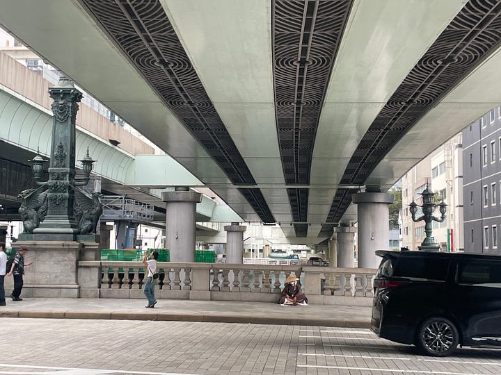 Four photographs of the bridge and the river beneath it, all of which are dominated by the expressway viaducts, which stand on thick concrete pillars dropped haphazardly into the river and fill almost its complete width, putting the bridge and river entirely into shade and blocking much of the sky.