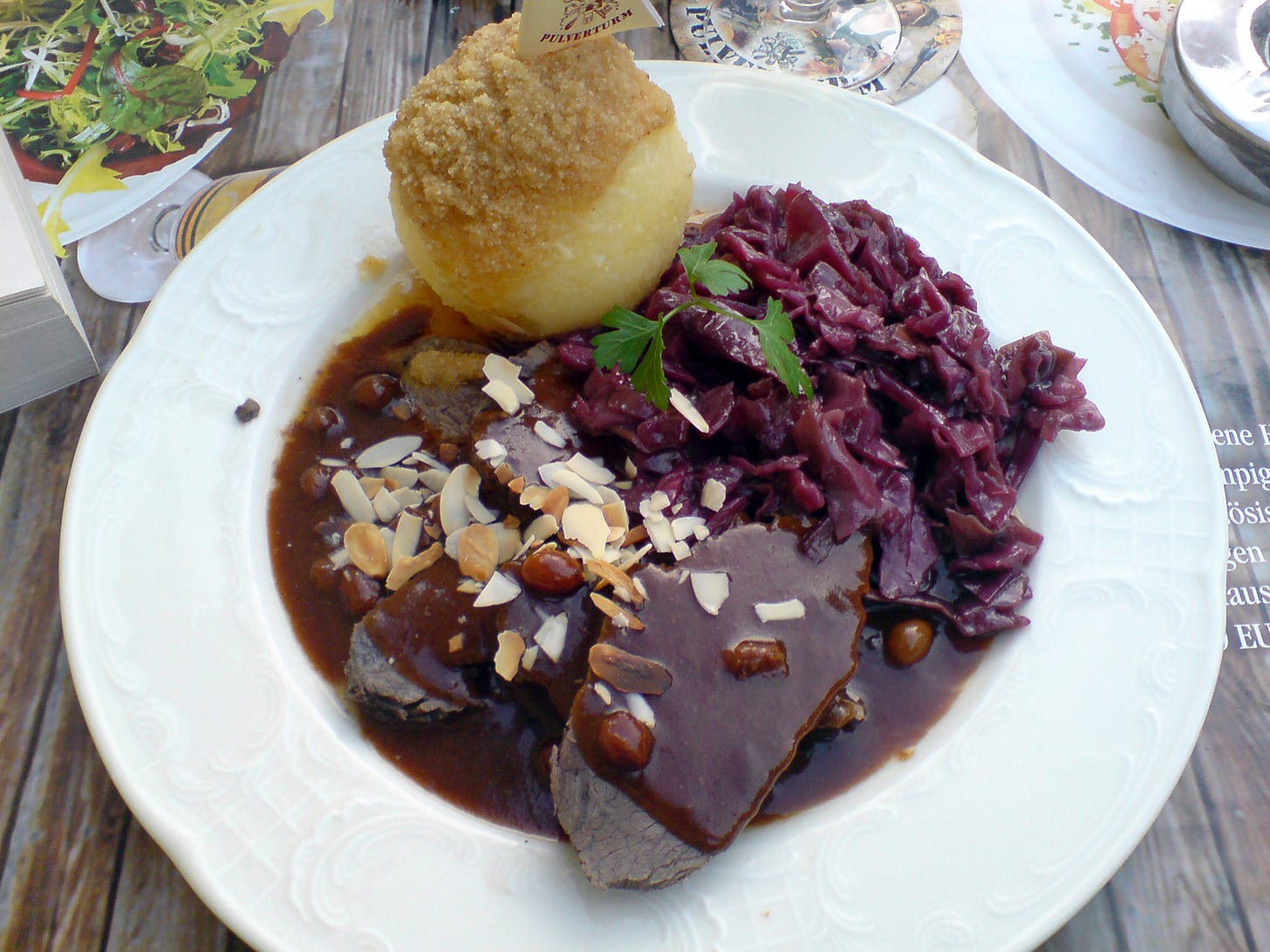 A photograph of a plate with beef, potato dumpling and red cabbage, served in Dresden