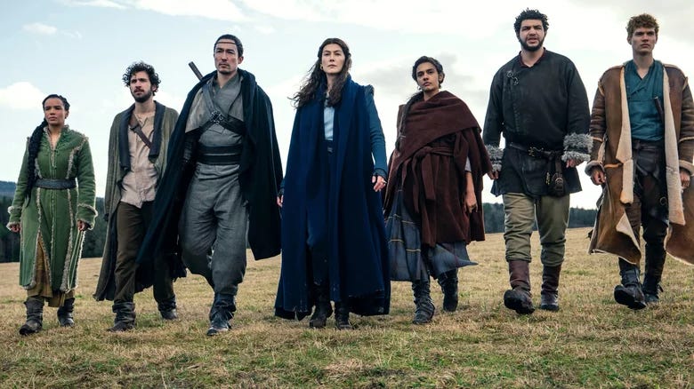 Cast of Wheel of Time from Season 1 walking across a field.
