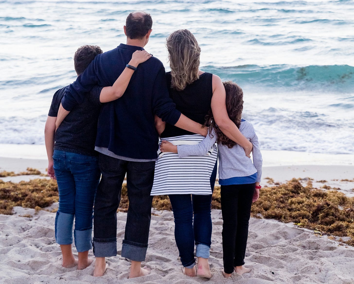 family arm in arm by beach