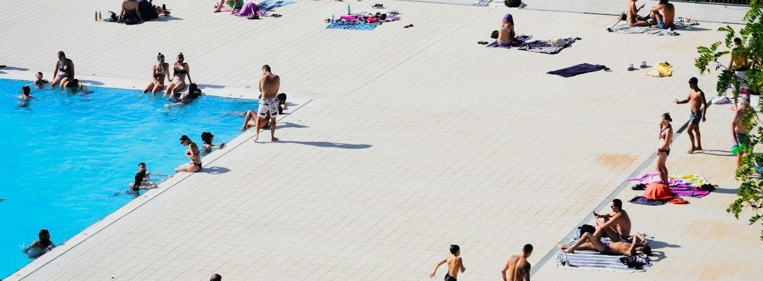 People enjoy a pool day overlooking a city. People enjoy a pool day overlooking a city.