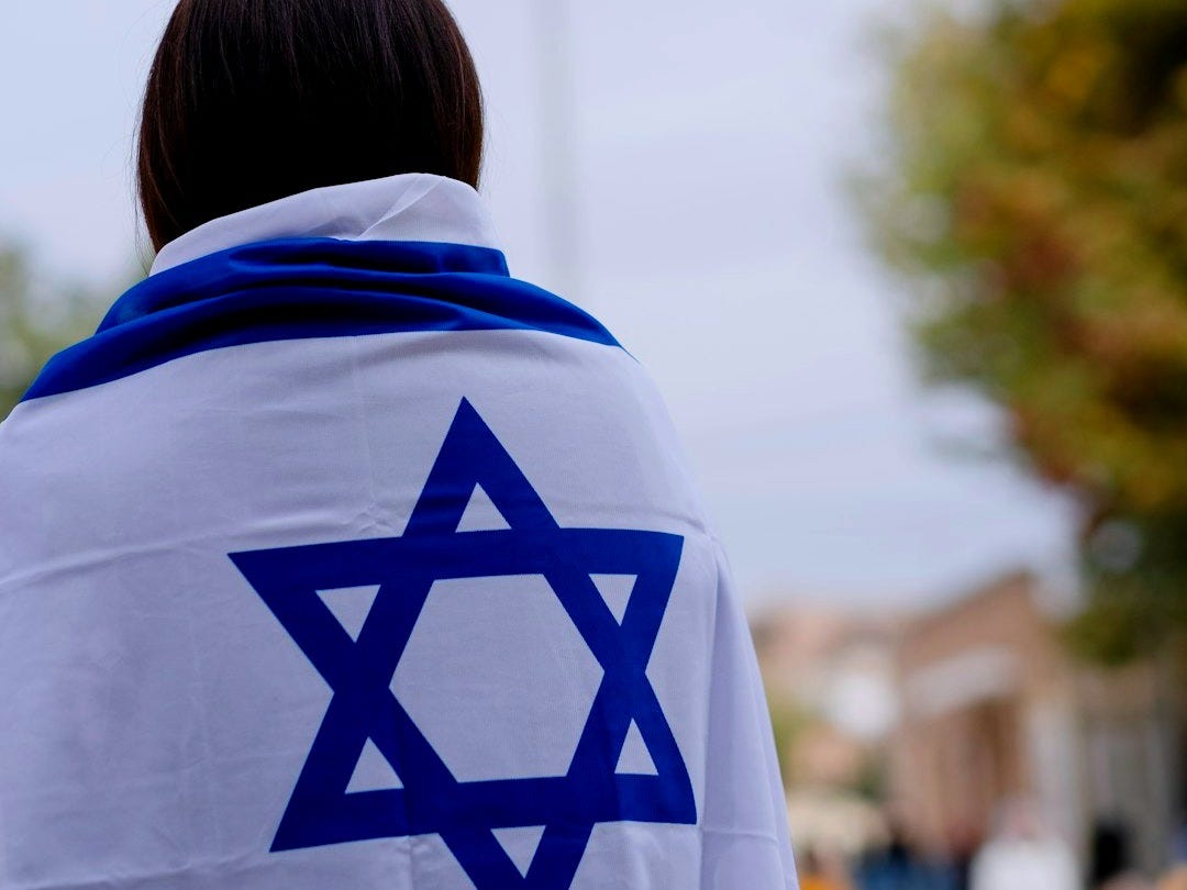 woman in white and blue hoodie standing near green trees during daytime