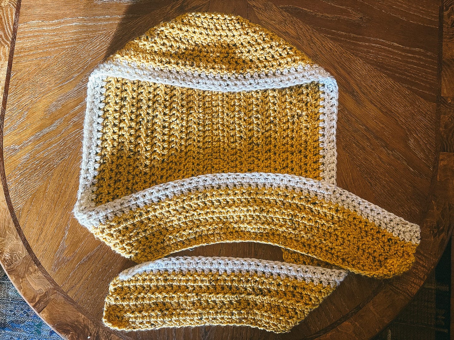 a yellow hooded scarf with white trim, crocheted in bulky yarn a yellow hooded scarf with white trim, crocheted in bulky yarn