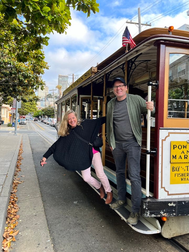 Nine photos of memoir coach Christine Wolf and her husband while they were dating. Photos include them holding a large white frame, dressed up for Christmas, riding a tandem bike, standing on a San Francisco trolley car, balancing on large tree trunks, and even allowing a little goat perch on Christine's back.