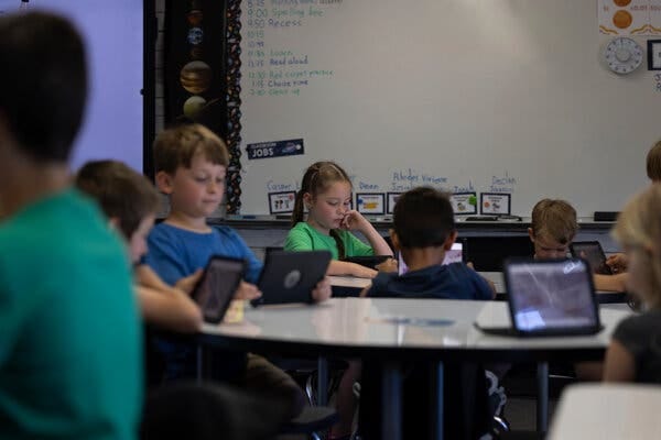 Young students in a classroom work on tablets. Young students in a classroom work on tablets.