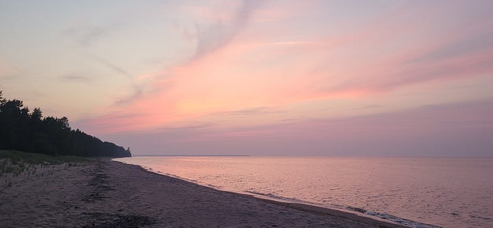 Shades of light pink in the sky mixed with clouds over Lake Superior.
