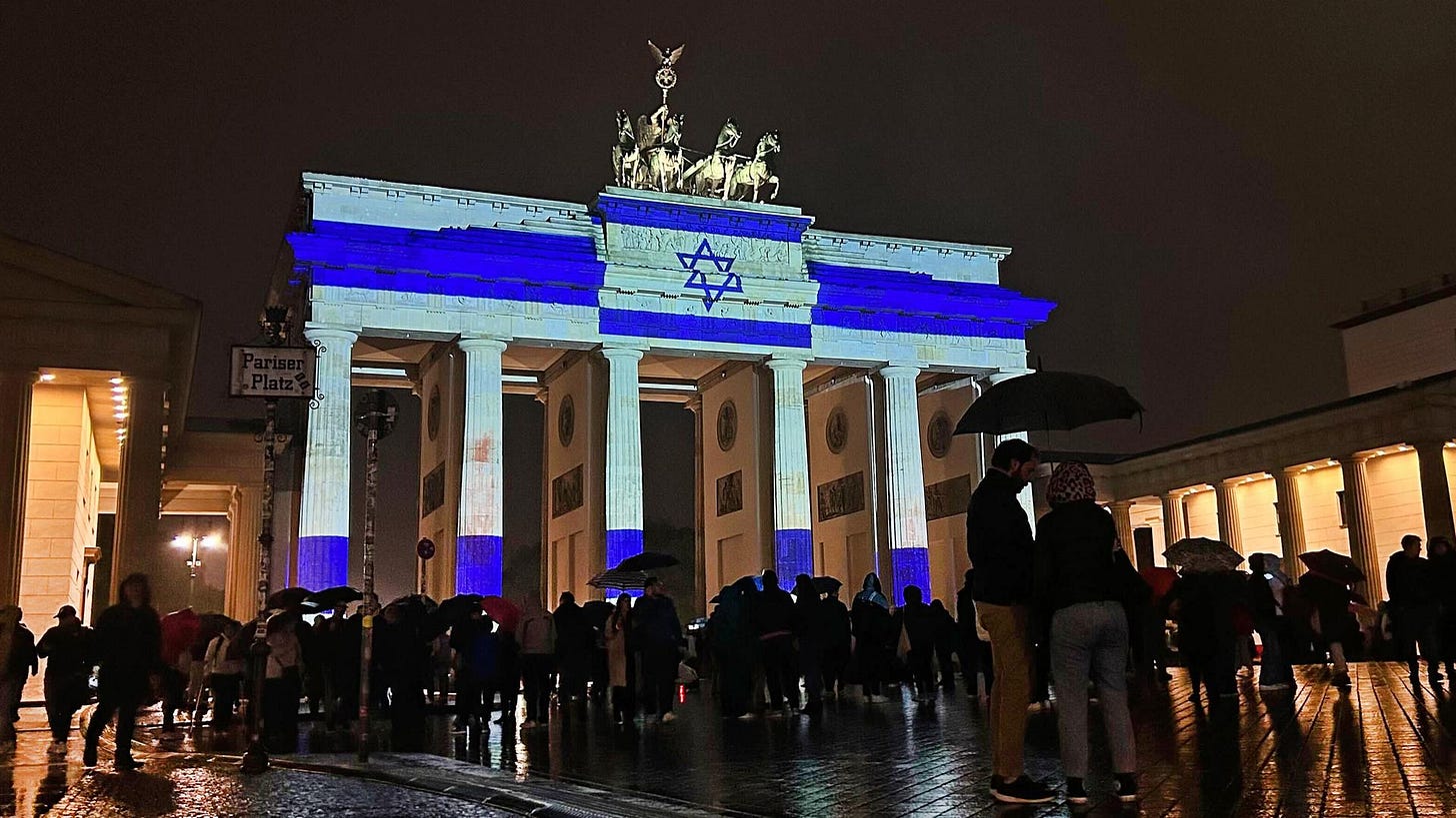 Zu sehen ist das Brandenburger Tor bei Nacht. Es wird hell in den Farben der blau-weißen Flagge Israels angestrahlt Zu sehen ist das Brandenburger Tor bei Nacht. Es wird hell in den Farben der blau-weißen Flagge Israels angestrahlt