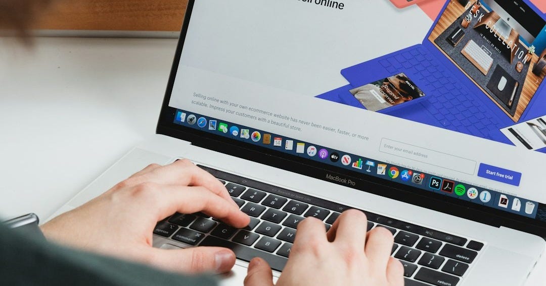 person using macbook pro on white table