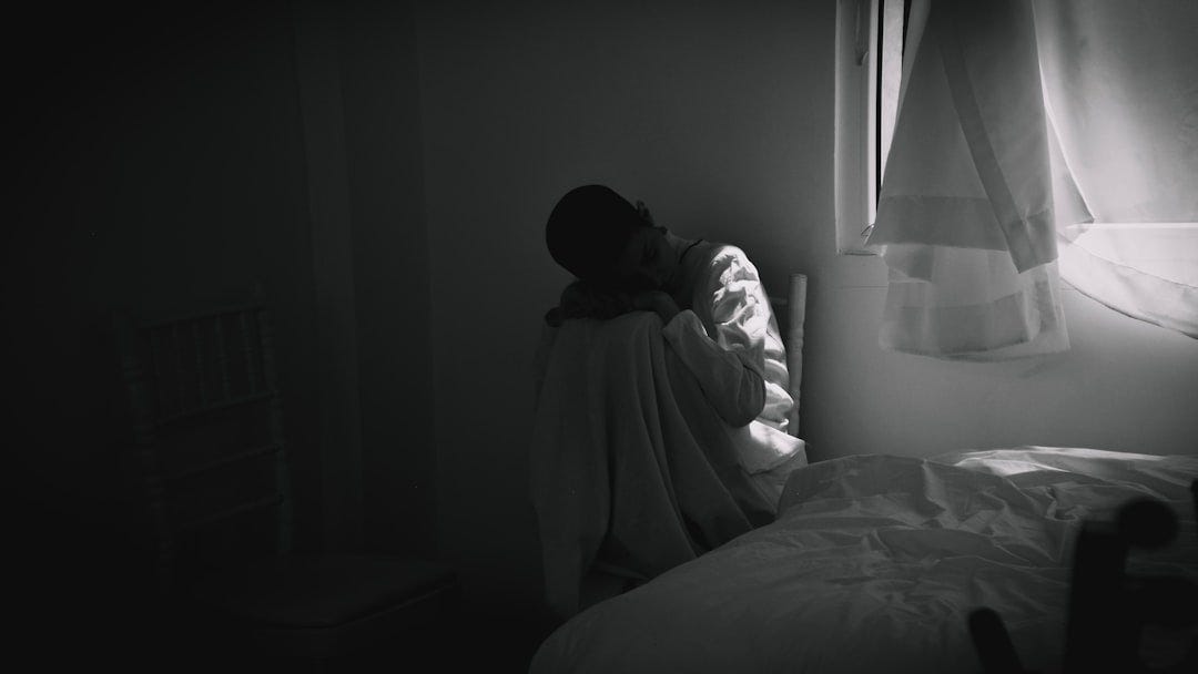 person in gray hoodie sitting on bed person in gray hoodie sitting on bed