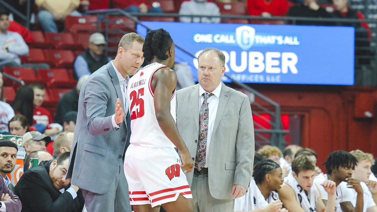 Wisconsin Badgers head coach Greg Gard and assistant Joe Krabbenhoft talk to guard John Blackwell on the sideline during a game. Wisconsin Badgers head coach Greg Gard and assistant Joe Krabbenhoft talk to guard John Blackwell on the sideline during a game.