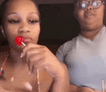 a woman is eating a lollipop while another woman watches .