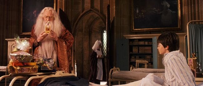 Frame da "Harry Potter e la pietra filosofale". Siamo nel pronto soccorso di Hogwarts, con il mago Albus Silente sulla sinistra che tiene in mano una confezione di caramelle Tuttigusti+1 e Harry Potter, seduto in un letto che lo guarda con faccia stupita.