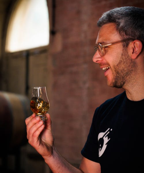 Lewis Hayes wearing a black t-shirt holding a glass with rum in it Lewis Hayes wearing a black t-shirt holding a glass with rum in it