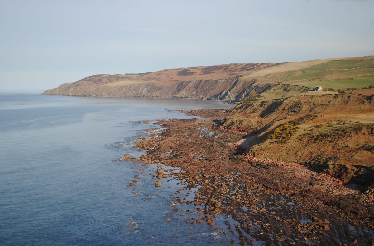 Rocky shoreline, fields above