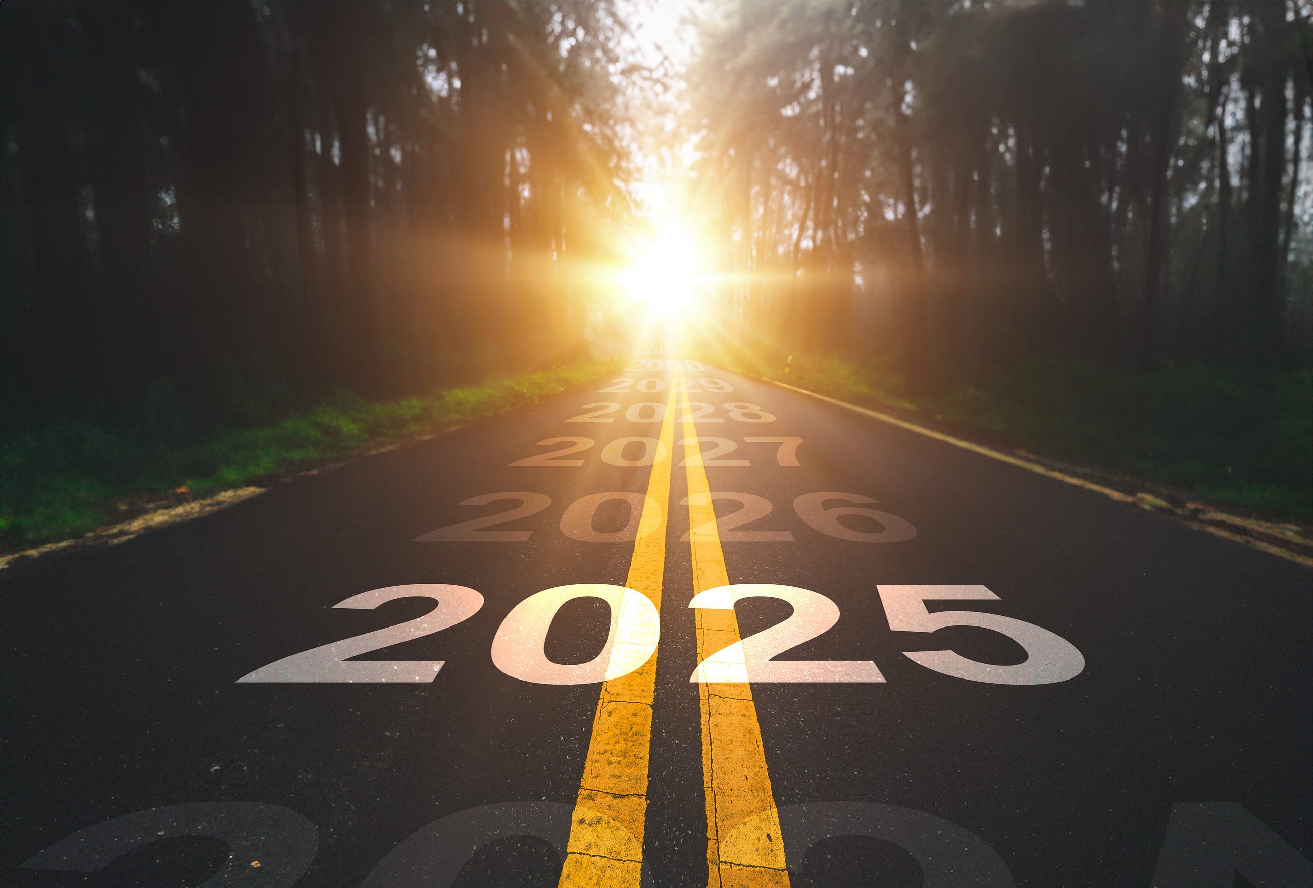 2025 written across a 2 lane road heading towards the sun 2025 written across a 2 lane road heading towards the sun