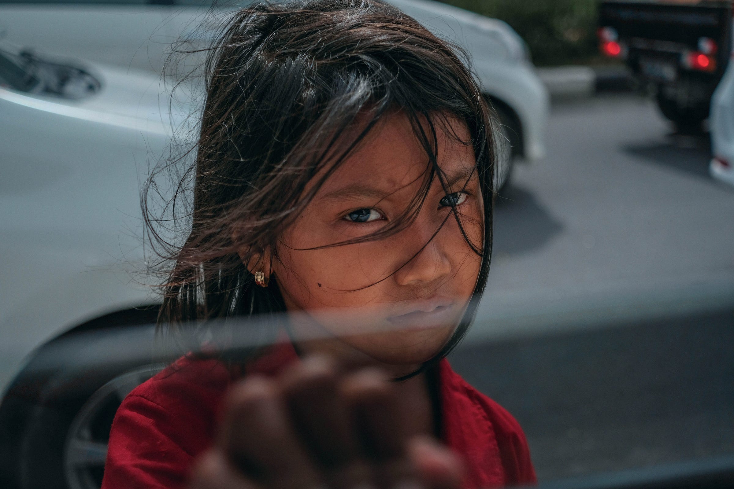 A child in the street, approaching a car window — looking at you with a sad but hopeful view in her eyes A child in the street, approaching a car window — looking at you with a sad but hopeful view in her eyes