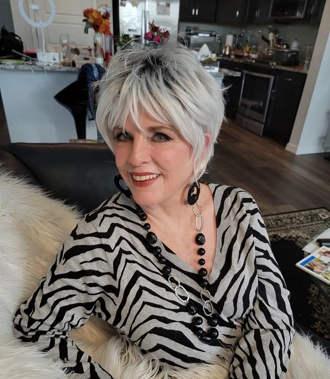 Beautiful and fancy older woman wearing a zebra striped top and black and silver accessories.