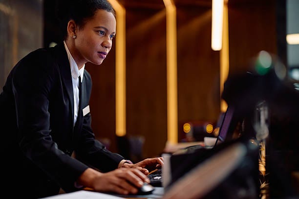 Black female receptionist working on a computer in a hotel.