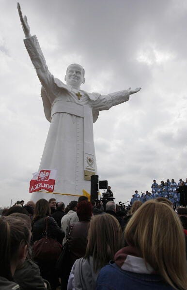 Residents attend the unveiling ceremony of the statue of the late Pope John Paul II in Czestochowa, Poland, on Saturday, April 13, 2013. Archbishop Waclaw Depo unveiled the 13.8-meter (45.3-foot) white fiberglass figure that was funded by a businessman, Leszek Lyson, in gratitude for what he believes was an intervention by the late pontiff in saving his drowning son. At front is a small replica statue. (AP Photo/Czarek Sokolowski)