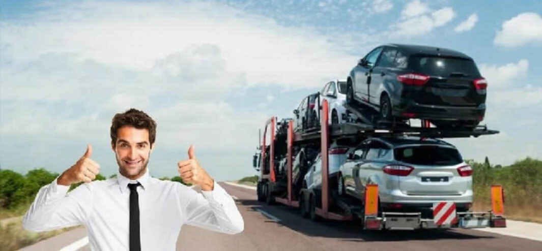 A broker with thumbs up next to an auto carrier on teh highway.