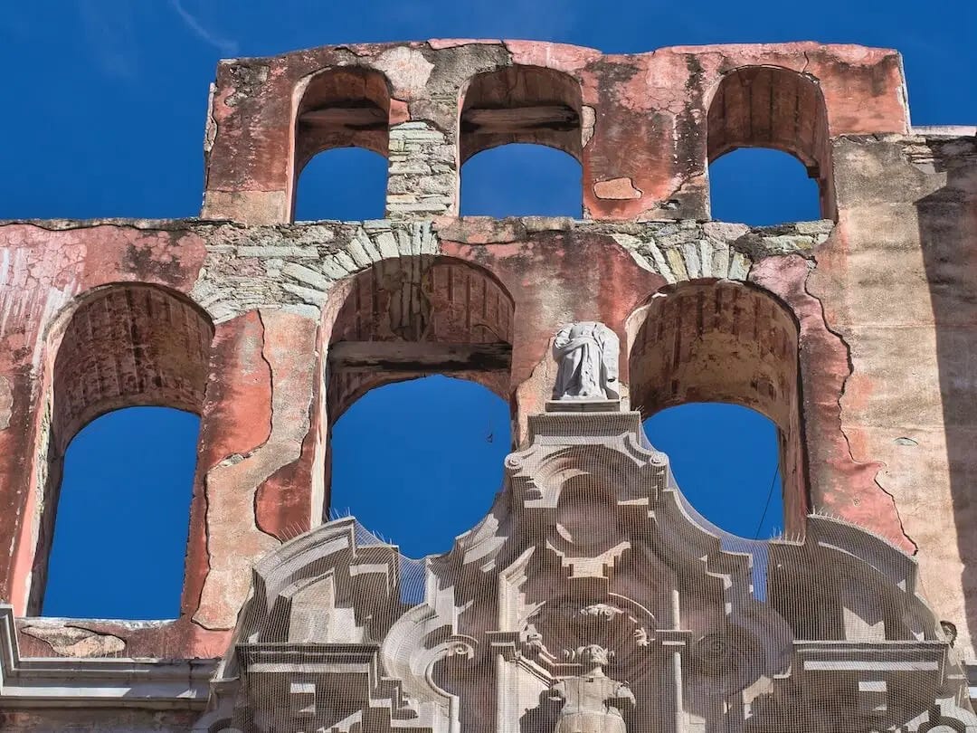 Two tiers of pink arches against a blue sky