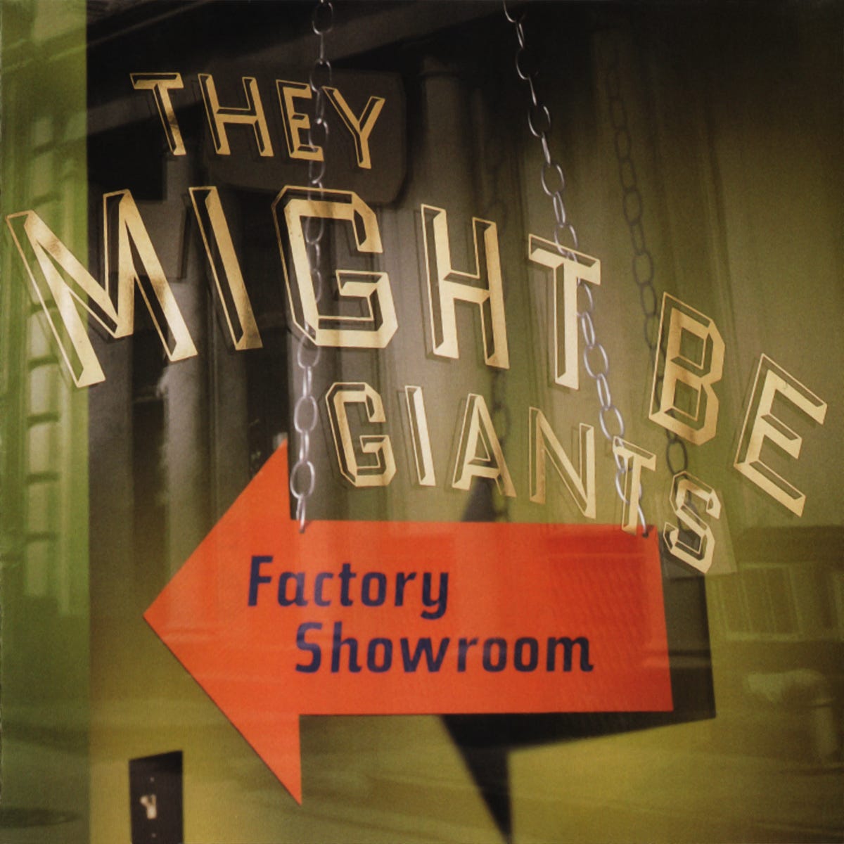 Album cover for Factory Showroom by They Might Be Giants. The image shows the band’s name in large, gold, 3D block letters hanging from chains like a store sign. Below it, a bright red arrow sign reads “Factory Showroom” in blue text, pointing to the right. The background features a blurred city street and glass reflections, evoking a storefront display. Album cover for Factory Showroom by They Might Be Giants. The image shows the band’s name in large, gold, 3D block letters hanging from chains like a store sign. Below it, a bright red arrow sign reads “Factory Showroom” in blue text, pointing to the right. The background features a blurred city street and glass reflections, evoking a storefront display.