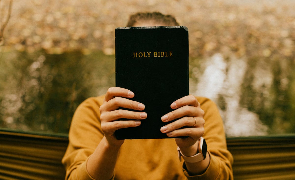 Man holding a Bible in front of his face Man holding a Bible in front of his face