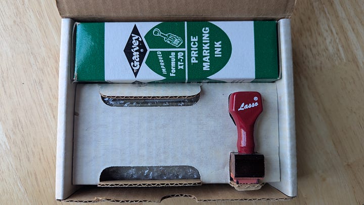a beat-up cardboard box with writing on the outside and some pencil marks, with another box and a rubber stamp inside