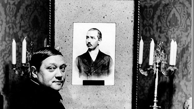 An oily cremator (Rudolf Hrušínský) looks at, to memory, a portrait of one of his ancestors.