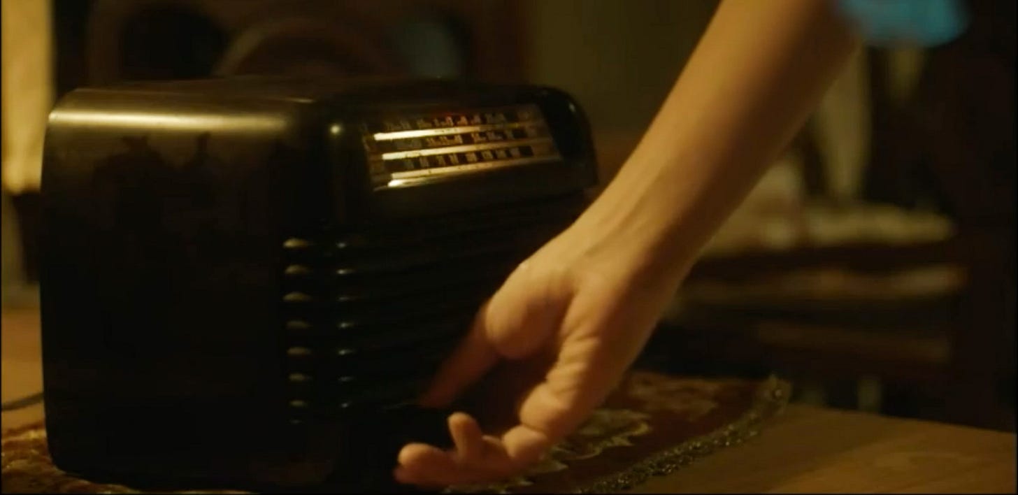 The hand of Qing Qianyi, one of the protagonists of A Touch of Green, turns the analog knob on a dusty black tabletop transistor radio.