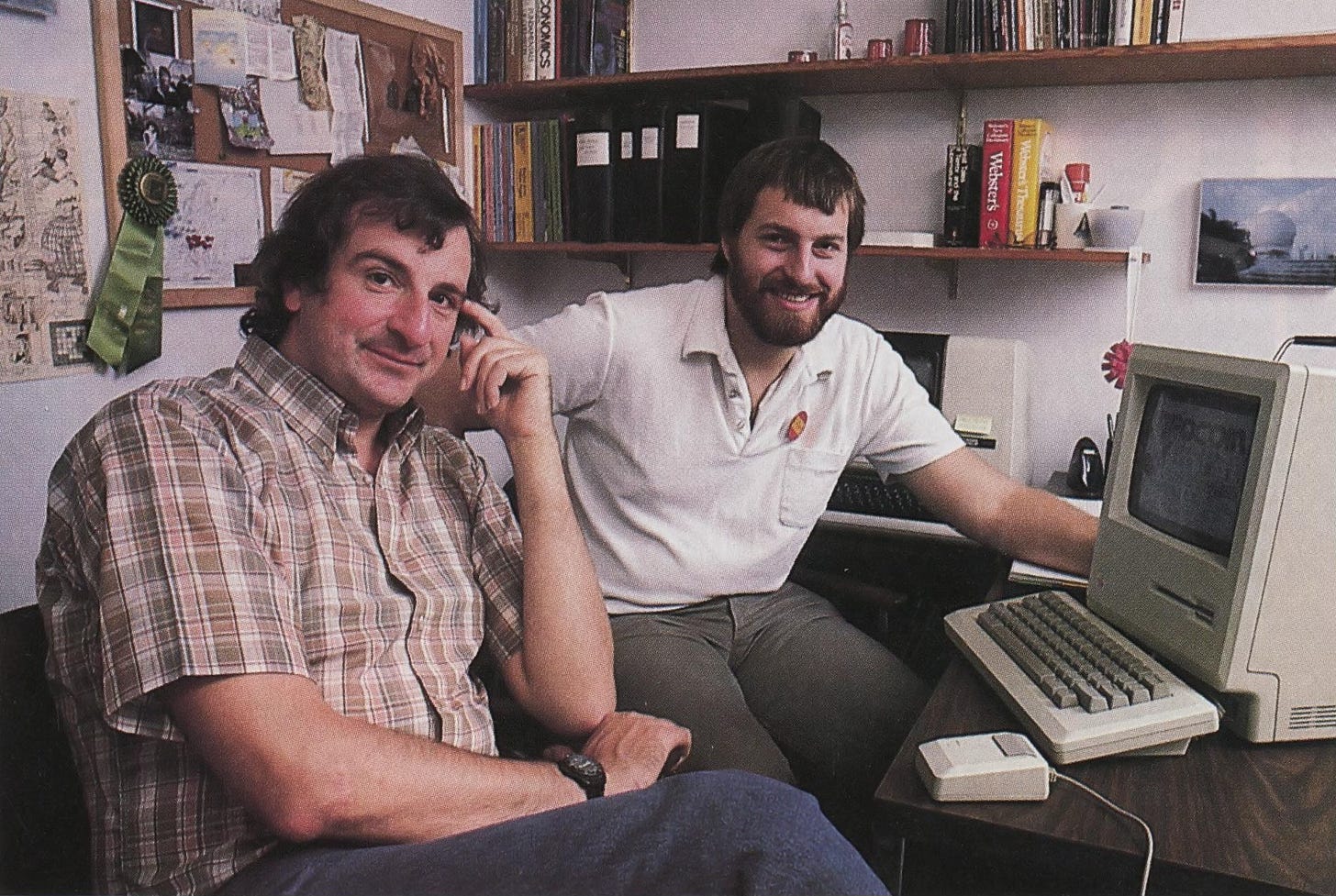 1984 photograph of Steve Meretzky with Hitchhiker’s Guide to the Galaxy author Douglas Adams sitting at a desk with an original Macintosh computer.