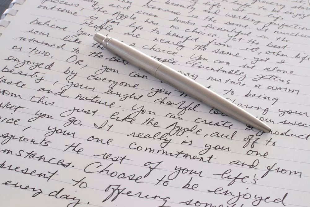 Loose leaf page covered in writing and a pen