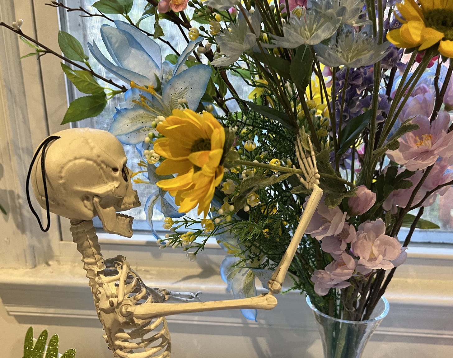 A toy skeleton smells a bouquet of flowers