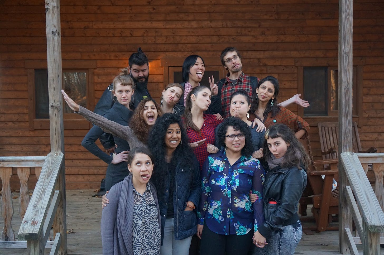 Multiracial group of RG staff, posing with goofy faces on the stairs of a house. 