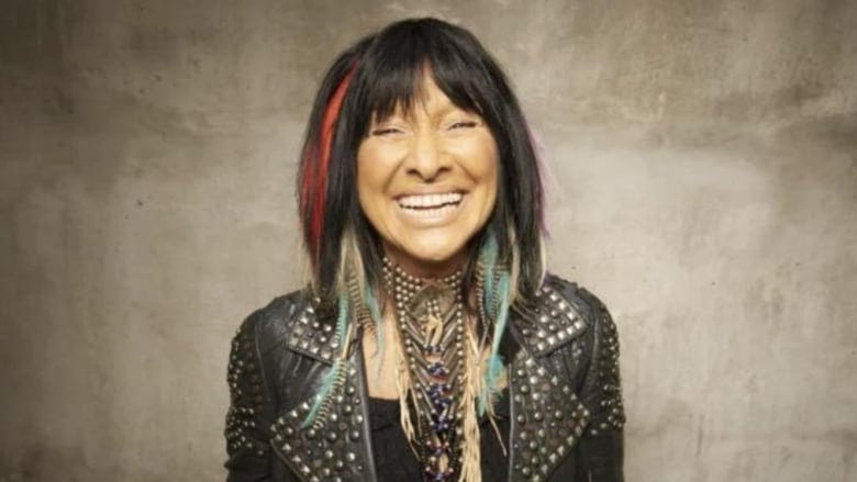 Indigenous woman with wide smile, black shirt and jacket with long feather earrings and necklace Indigenous woman with wide smile, black shirt and jacket with long feather earrings and necklace