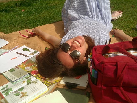 girl on the picnic blanket journaling with art supplies