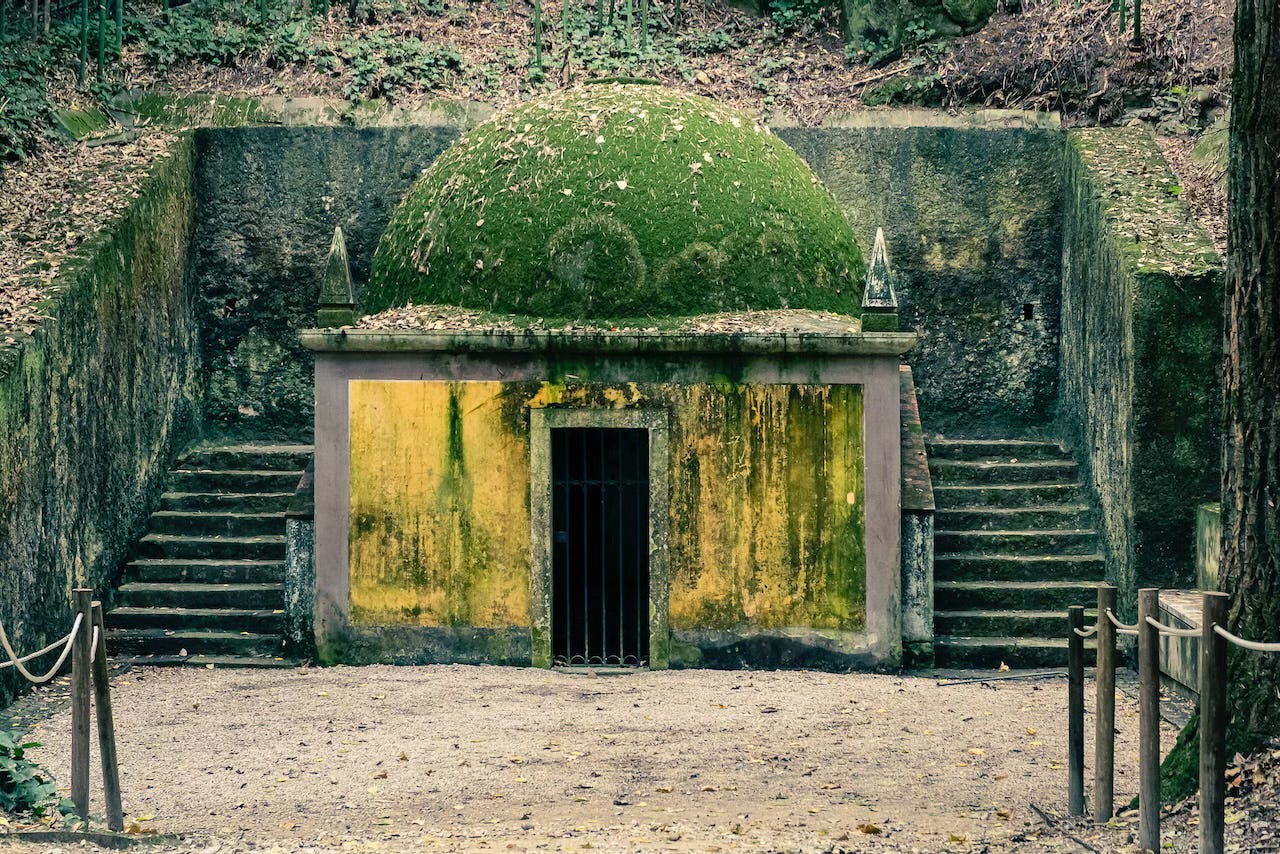 A small chapel with yellow walls and a dome in the forest, in Coimbra.