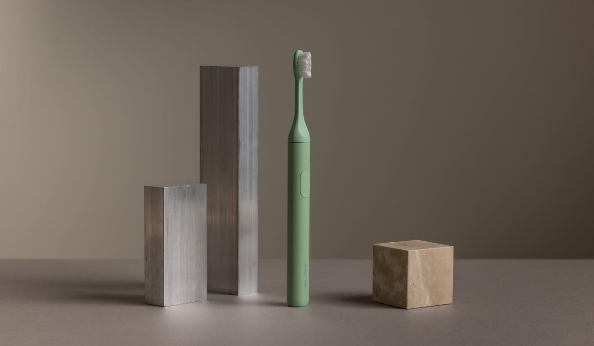 Green SURI toothbrush against a neutral background