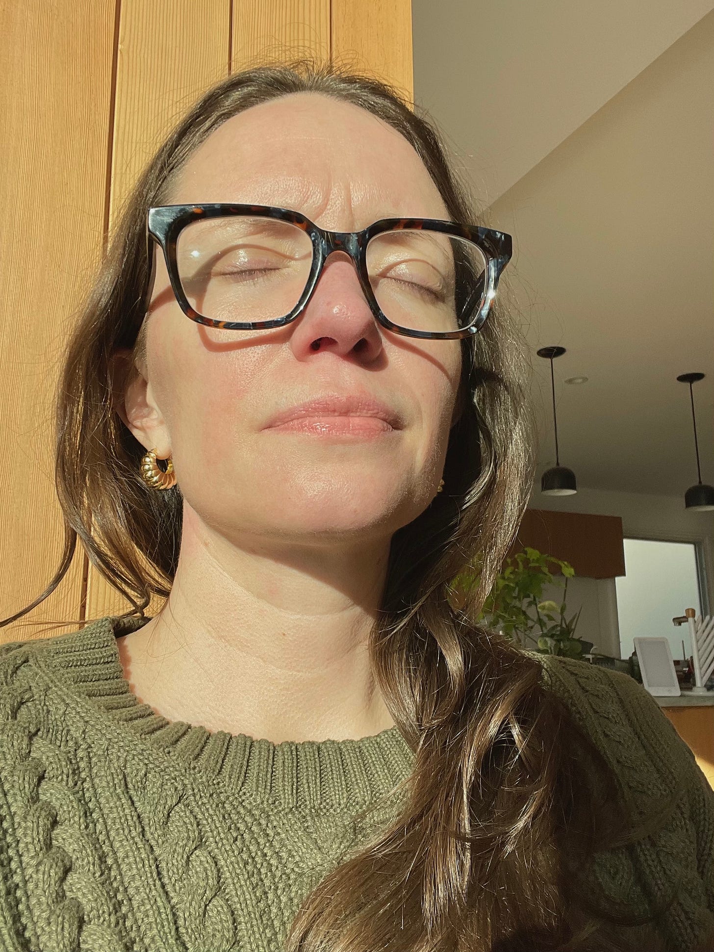 Jessica, a white woman, faces the winter sun with her eyes shut